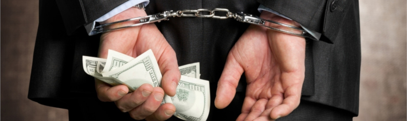Man in business suit handcuffed while holding cash