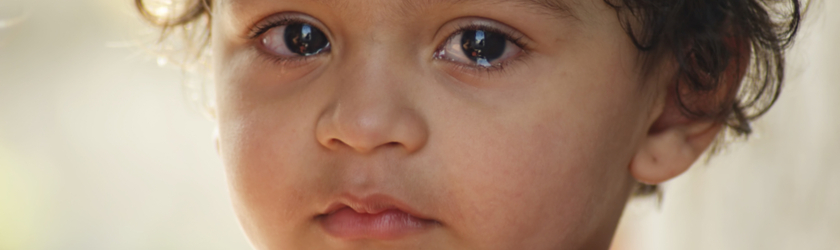 Close up portrait of a toddler looking at the camera with tears in its eyes